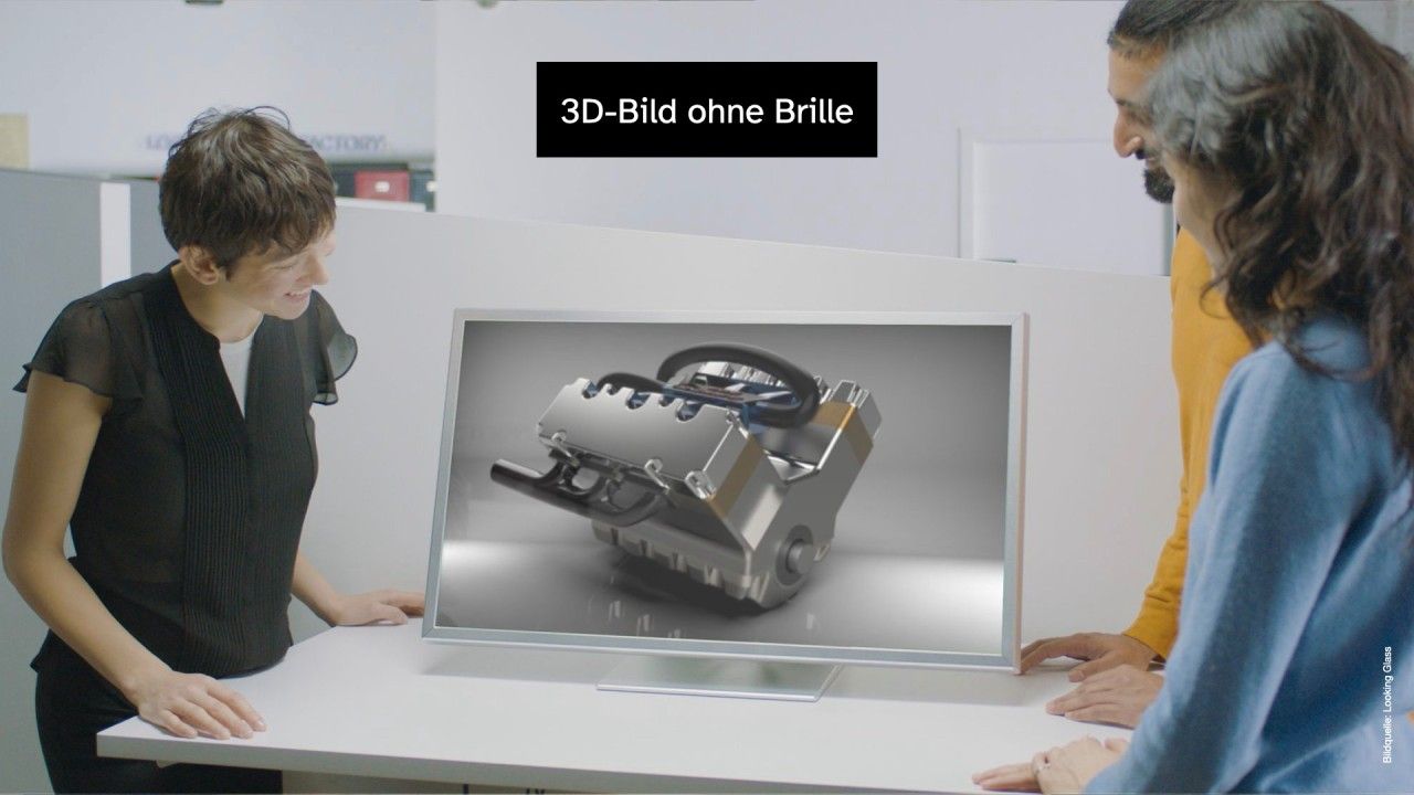 Mehrere Personen stehen um einen autostereoskopischen Monitor, der einen Motorblock zeigt