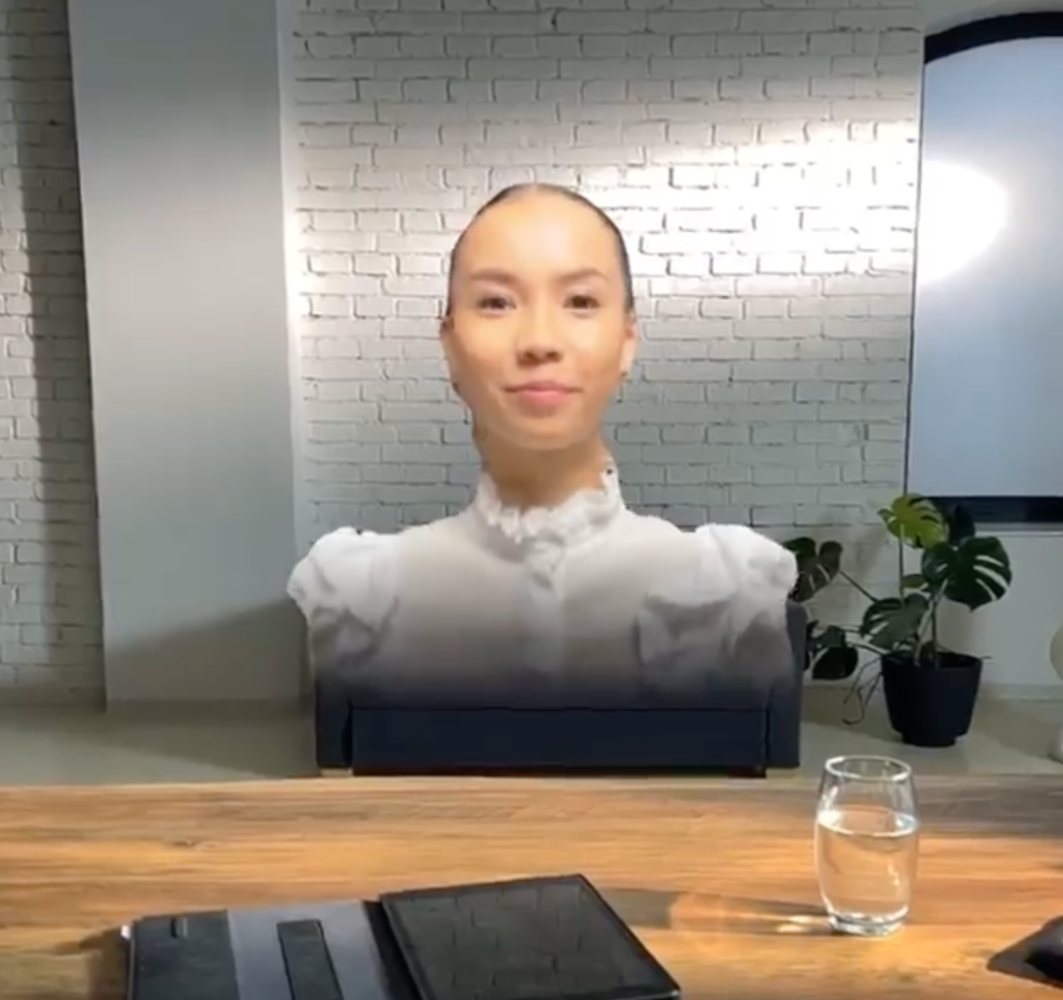 Holo einer Frau hinter einem Schreibtisch