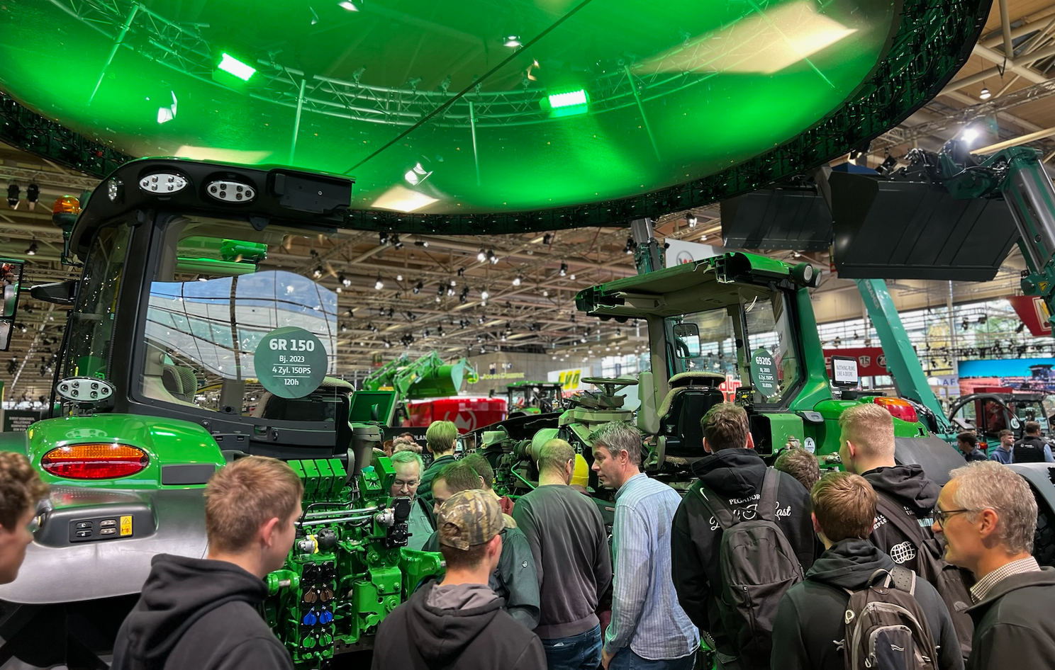Viele Leute an einem Messestand mit grünem John Deere Traktor
