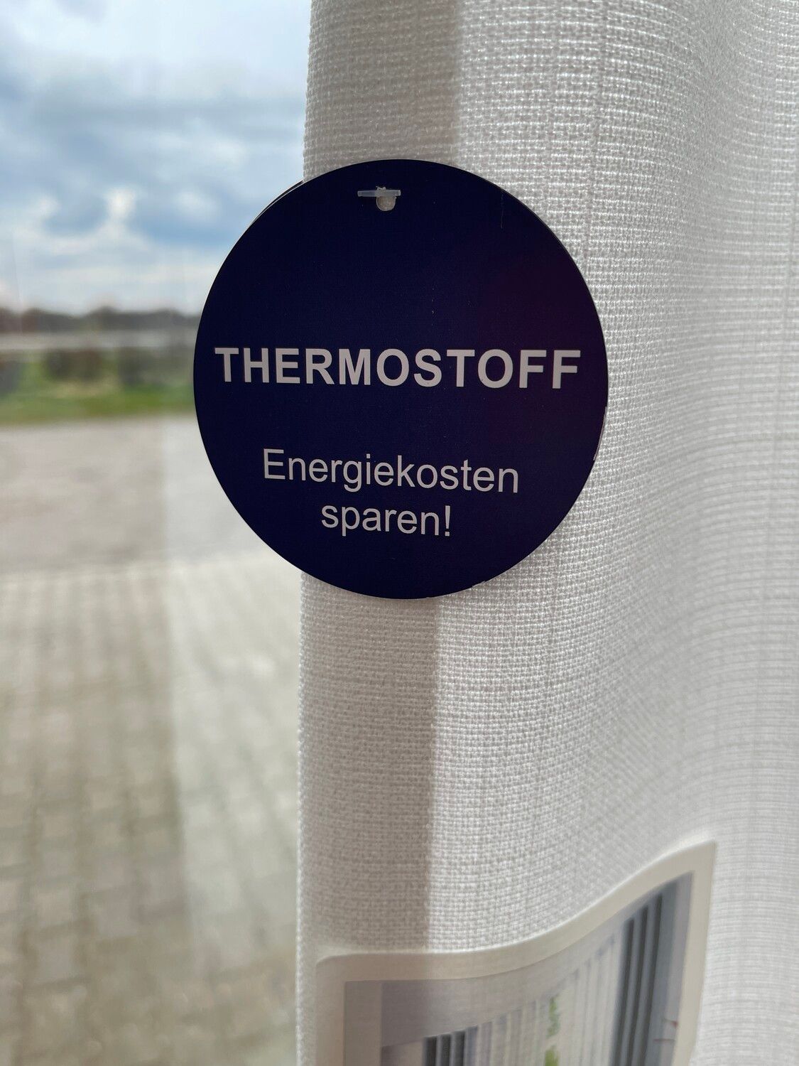 Thermostoff-Schild an Gardine